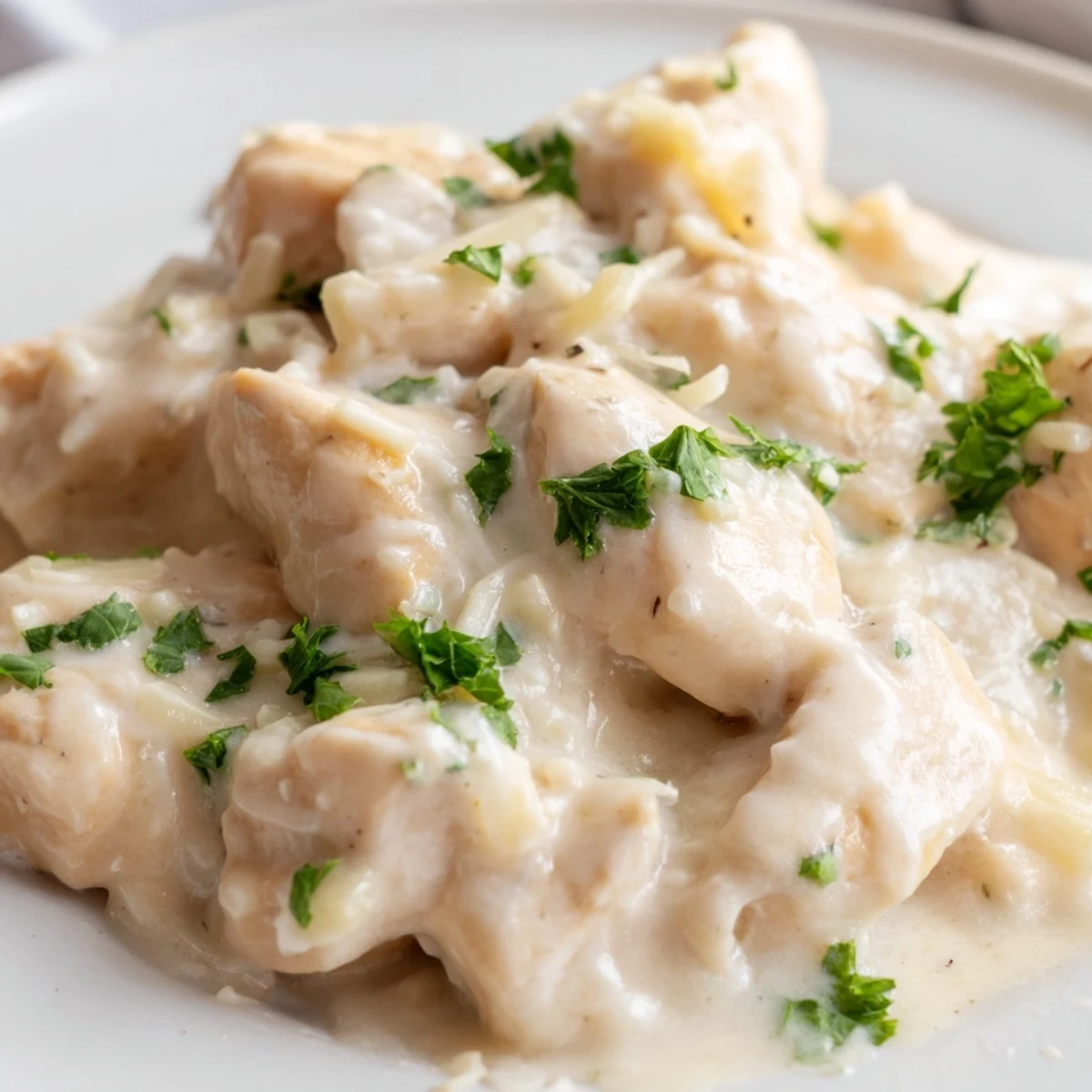 Close up of creamy slow cooker chicken with shredded Parmesan coating the thick sauce