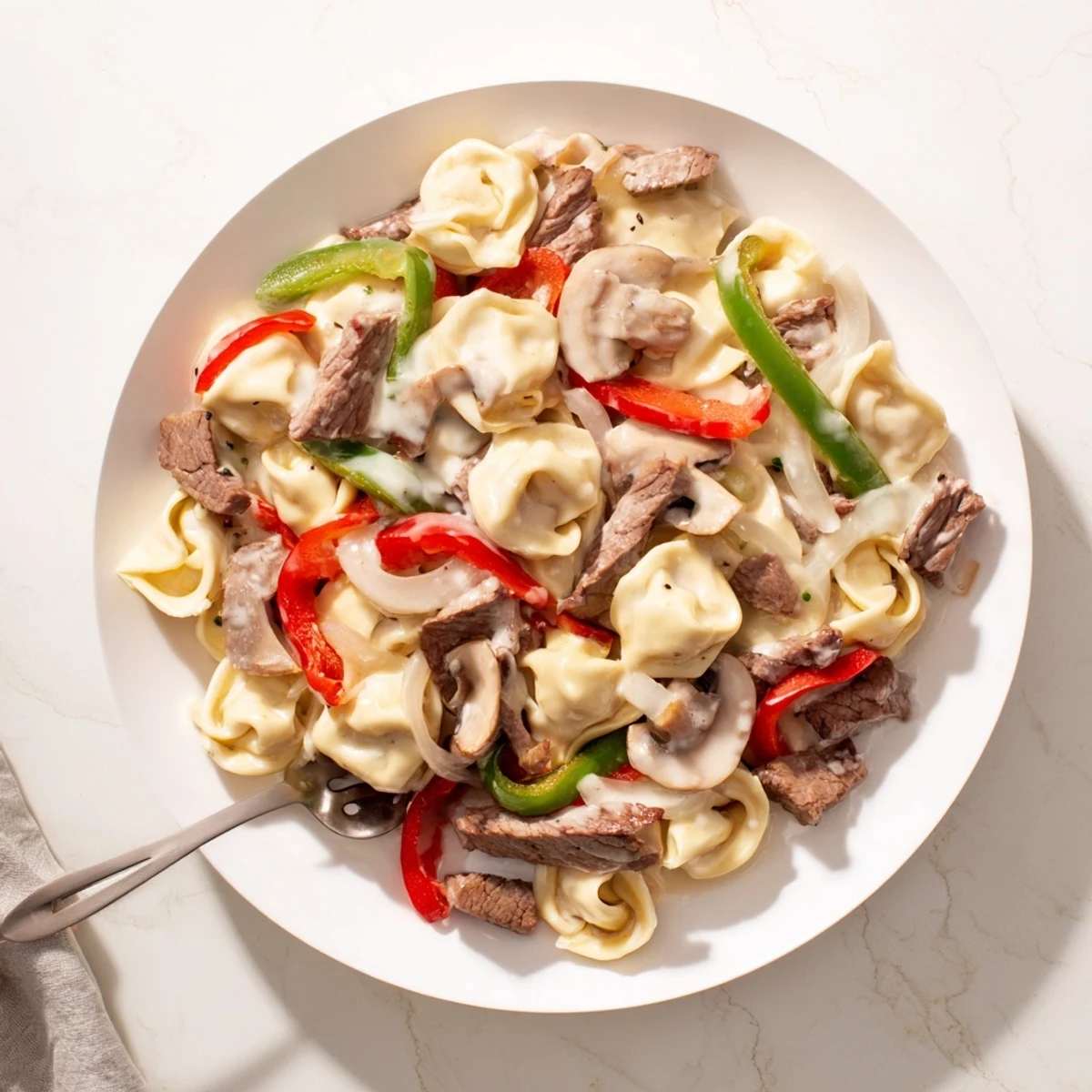 Creamy Crock Pot cheesesteak tortellini with tender beef, colorful peppers, and melted provolone cheese
