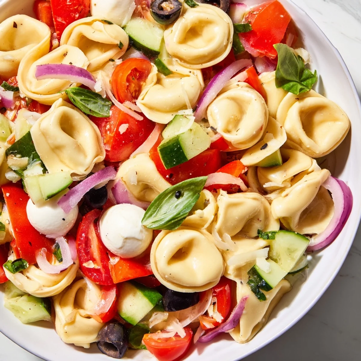 Colorful tortellini salad with cherry tomatoes, cucumber, and mozzarella tossed in Italian dressing