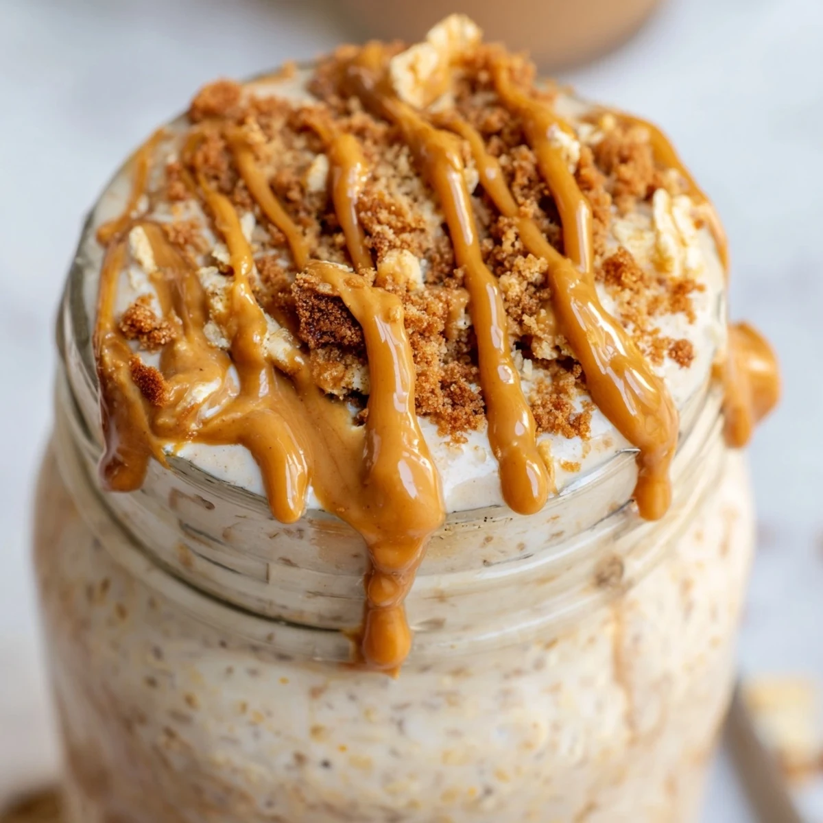 Creamy Quick Biscoff Overnight Oats topped with crushed cookies in a glass jar