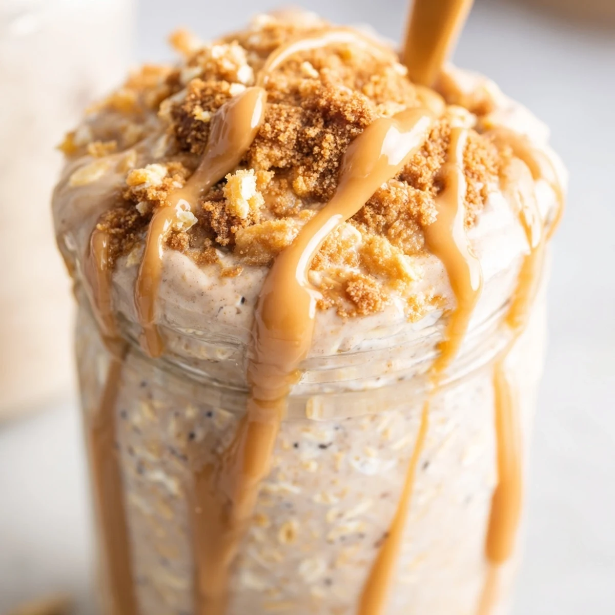 Quick Biscoff Overnight Oats swirled with caramel-colored spread and crunchy cookie crumbles