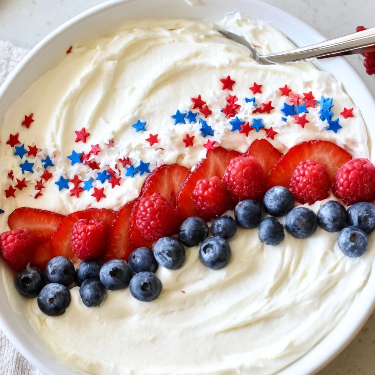 Star Spangled Cheesecake Dip topped with juicy berries and patriotic sprinkles