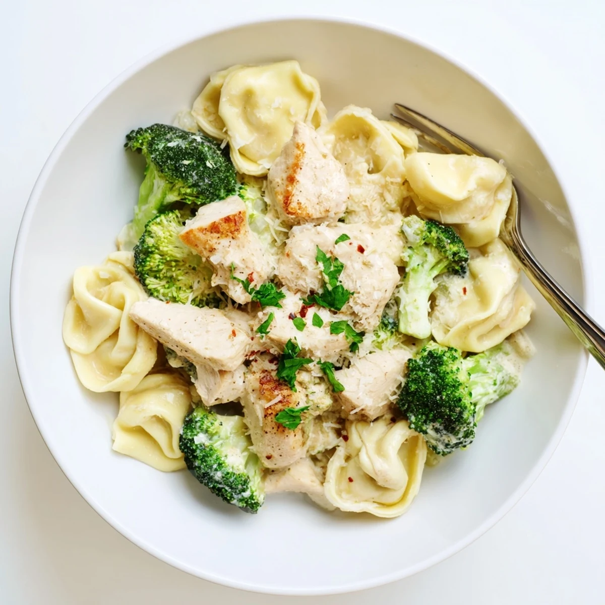 Skillet steaming with garlic cream, tender chicken—Creamy Garlic Parmesan Tortellini Chicken Broccoli Recipe.