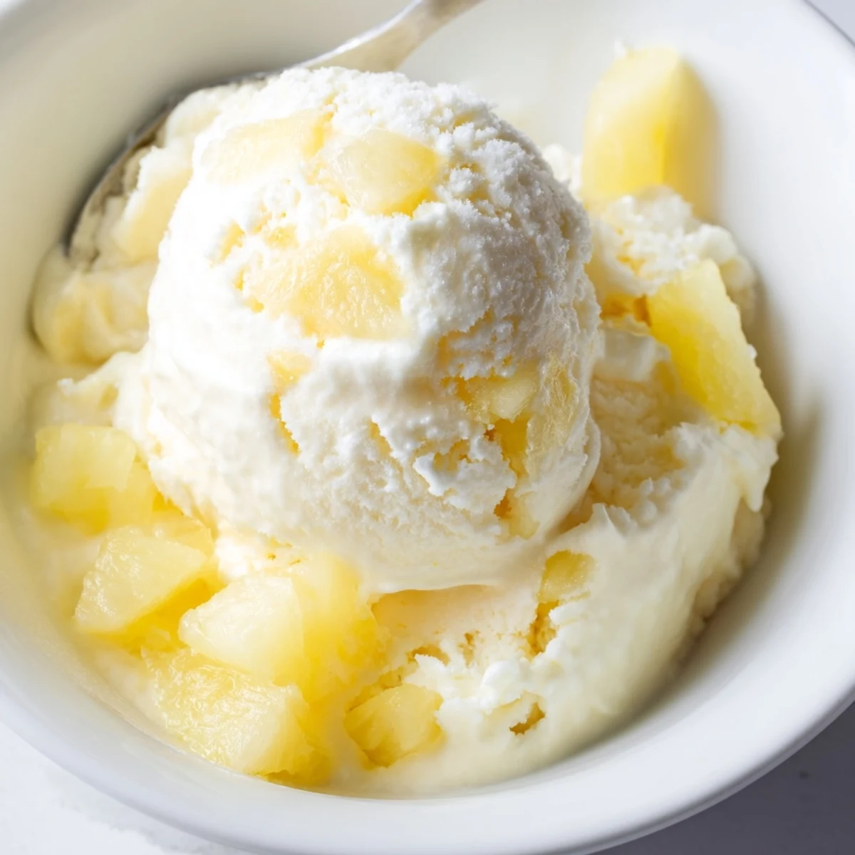 A chilled bowl of Creamy Pineapple Ice Cream topped with toasted coconut.