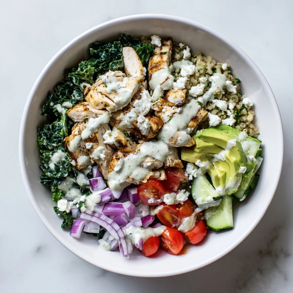 Sliced marinated chicken breast over massaged kale with cherry tomatoes, cucumber, avocado, and crumbled feta cheese